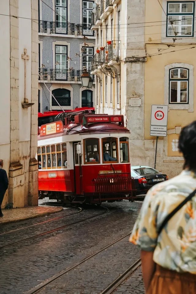 A red tram climbing a cobbled street in Lisbon