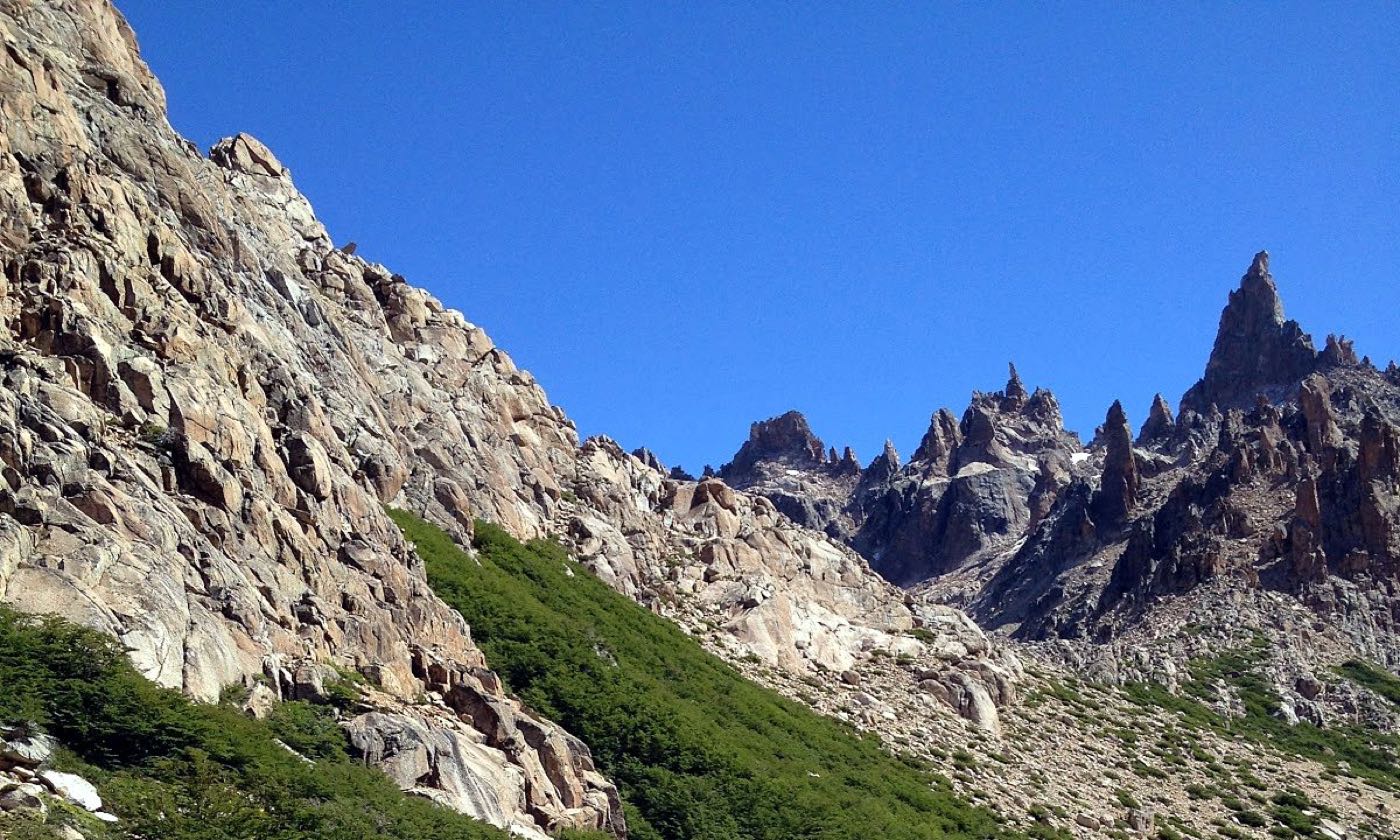 Jagged granite spires above green slopes near Refugio Frey, Bariloche